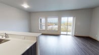 Located at 3410 Orlando St in Port Orchard, Washington, this well-appointed second-floor unit offers a thoughtfully designed, single-level layout that blends modern finishes with comfortable everyday living. The open-concept living and kitchen area is anchored by durable hardwood-style plank flooring that runs throughout the main living spaces, creating a cohesive and contemporary aesthetic. Neutral-toned walls and ample natural light from large windows contribute to a bright and airy atmosphere. The living area opens directly to a private balcony through a sliding glass door, offering pleasant views of the surrounding treeline and neighborhood. The kitchen is equipped with stainless steel appliances, including a full-size refrigerator, electric range, and dishwasher, complemented by dark wood cabinetry and clean white countertops that provide generous prep and storage space. The bedrooms are carpeted for comfort and feature neutral walls and good-sized closets with built-in shelving for organized storage. Natural light filters into the bedrooms through well-placed windows. The overall design of the unit is clean and modern, offering a move-in-ready space with quality finishes throughout.