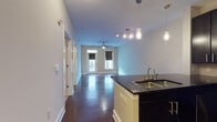 Located in Charlotte's vibrant 28204 zip code, this single-floor residence at 808 Hawthorne Lane offers a well-designed open-concept layout that seamlessly connects the living and kitchen areas. Rich, dark hardwood flooring flows throughout the main living spaces, complemented by neutral walls and generous natural light from multiple windows fitted with roller shades.

The kitchen is a standout feature, boasting dark espresso cabinetry that reaches toward the ceiling, granite countertops, a decorative tile backsplash, and a full suite of stainless steel appliances including a gas range, built-in microwave, and French door refrigerator. A peninsula with a double basin sink and pendant lighting serves as both a functional workspace and a visual anchor connecting the kitchen to the open living area.

The living area is spacious and versatile, equipped with a ceiling fan and track lighting, and benefits from natural light streaming through large windows and a glass-paneled door. A secondary room, also featuring hardwood floors, a ceiling fan, and dual windows, offers flexible use as a bedroom or office.

The bathroom is finished with warm stone-toned tile flooring, a dark vanity with white countertop, and a tiled tub-shower combination with accessible grab bars. The overall ambiance of the space is modern and functional, with a cohesive dark-and-light contrast design aesthetic throughout.