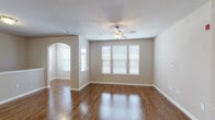 This single-floor 1-bedroom, 1-bathroom residence combines practical design with attractive finishes throughout its thoughtfully arranged layout. Rich, dark hardwood-style flooring runs continuously through the main living areas, creating a warm and cohesive aesthetic. The spacious living room features a ceiling fan, a textured ceiling, and multiple windows fitted with white blinds that invite generous natural light. An elegant arched passageway connects the living area to adjoining spaces, adding a classic architectural touch. The open-concept kitchen is a standout feature, equipped with dark espresso cabinetry, granite-style countertops, and a full suite of black appliances including a refrigerator, range, microwave, and dishwasher. A built-in wine rack accent and pendant lighting over the kitchen bar add a refined, functional detail. The kitchen flows seamlessly into the main living space, making it ideal for everyday living and entertaining. The bedroom offers a quiet retreat with a well-sized window and direct access to a closet. The bathroom mirrors the kitchen's design language with a dark vanity, matching granite-style countertop, a large mirror, and a tub-shower combination. A dedicated storage closet provides added convenience within the unit.