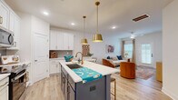 Located at 9100 Bluedale Road in Charlotte, NC, this two-story home offers four bedrooms and four bathrooms thoughtfully distributed across both floors. The entry foyer welcomes you with light wood flooring and a staircase featuring a classic wood banister with white risers, leading to the upper level. The open-concept main floor seamlessly connects the kitchen and living room, creating an inviting and functional gathering space. The kitchen is a standout, showcasing white shaker cabinetry with gold hardware, a navy blue island topped with white quartz countertops, a tile backsplash, stainless steel appliances, and dual gold pendant lights. The living area features natural light from multiple windows with tasteful drapery. The bedrooms are bright and comfortable, each benefiting from natural light and hardwood-style flooring. The primary bedroom includes a dedicated walk-in closet with built-in shelving and an en suite bathroom complete with a glass-enclosed, marble-tiled walk-in shower and a white vanity. Additional bathrooms mirror the same clean, modern aesthetic. Three closets and a hallway round out the functional layout of this well-designed Charlotte home.