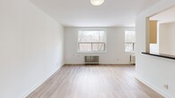 Located at 5 Stag Hill Drive in Toronto's east end, this well-appointed 1-bedroom, 1-bathroom unit offers a clean, modern aesthetic across a thoughtfully laid-out single floor. Light hardwood flooring runs throughout, complementing the bright white walls and creating a cohesive, airy atmosphere.

The open-concept living room is generously sized, featuring large windows with views of surrounding trees and classic cast-iron radiators that add a charming architectural detail. Natural light fills the space throughout the day. The kitchen is designed in a sleek galley style, outfitted with cream cabinetry, dark countertops, stainless steel appliances including a built-in oven, microwave, refrigerator, and dishwasher, plus a window that overlooks the treetops.

The spacious primary bedroom offers ample room, a large sliding-door closet, a radiator for heating, and a window with natural views, creating a calm and comfortable retreat. The bathroom is finished with grey tile surrounds, a soaking tub with overhead shower, a dark vanity with integrated sink, and a mirrored medicine cabinet. A hallway connects all areas efficiently, completing this practical and well-finished unit.