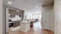 This thoughtfully designed one-bedroom, one-bathroom residence offers a functional and modern living experience across a single floor. The open-concept kitchen and living area serves as the heart of the home, where the kitchen impresses with rich taupe cabinetry, a white subway tile backsplash, granite countertops, a central island with bar seating, and a full suite of stainless steel appliances including a refrigerator, range, microwave, and dishwasher. Wood-style plank flooring runs seamlessly throughout the entire unit, providing a warm, cohesive aesthetic. The living room is bright and inviting, featuring large windows that draw in abundant natural light, a ceiling fan, and a glass door that opens to a private outdoor balcony with exterior views. The bedroom is a comfortable and quiet retreat, complete with its own ceiling fan, a window with outdoor views, and direct access to a spacious walk-in closet outfitted with multi-level wire shelving for ample storage. The bathroom is well-appointed with a dark wood vanity topped with a granite countertop, a large mirror, and a full soaking tub with a tiled surround. The overall ambiance is clean, contemporary, and move-in ready.