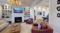 Located at 1001 Archdale Dr in Franklin, Tennessee, this single-story community space blends modern farmhouse aesthetics with thoughtfully designed gathering areas. The entryway makes a strong first impression with crisp white shiplap walls, rich hardwood flooring, a statement beaded chandelier, and a central round accent table. Warm wood-framed glass double doors welcome visitors with an abundance of natural light.

The living area is anchored by a classic fireplace with a refined white mantel, flanked by built-in shelving and cabinetry. A coffered ceiling with an elegant chandelier adds architectural interest, while large windows dressed with floor-length curtains invite natural light and views of the outdoors.

Flowing seamlessly from the living space is a generously sized kitchen and lounge area, featuring a bold navy island with crisp white countertops, pendant lantern lighting, and a farmhouse sink along the perimeter cabinetry. The open layout transitions naturally into a recreation zone complete with a billiard table and wall-mounted display screen, making it ideal for social gatherings.

Throughout the space, consistent hardwood flooring, shiplap wall accents, and carefully curated lighting create a cohesive, welcoming atmosphere that embodies relaxed Southern charm with upscale detail.