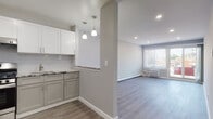 Located at 90 Lupton Lane, this single-floor unit showcases a thoughtfully renovated interior with a clean, modern aesthetic throughout. The open-concept layout seamlessly connects the kitchen and living area, creating a bright and functional living space. Durable light-toned hardwood-style flooring runs through the main living areas, complementing the soft gray and white color palette on the walls.

The kitchen is well-appointed with two-tone cabinetry — white upper cabinets and gray lower cabinets — topped with granite-style countertops. Stainless steel appliances include a gas range and a full-size refrigerator, and elegant pendant lighting hangs above the kitchen pass-through, adding a stylish touch. A subway tile backsplash ties the kitchen design together.

The spacious living room benefits from a sliding glass door and a large window that invite natural light and provide outdoor views. Baseboard heating and a wall-mounted air conditioning unit ensure year-round comfort. The bedroom features plush carpeting, a window with natural light, and its own baseboard heater. The bathroom is finished in crisp white tile with a gray vanity, a mirrored medicine cabinet, and a full tub-shower combination, delivering a clean and functional design.