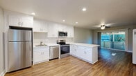 Located at 37811 Fremont Blvd in Fremont, CA, this thoughtfully designed one-bedroom, one-bathroom unit offers a comfortable and functional layout across a single floor. The open-concept kitchen and living area forms the heart of the home, showcasing crisp white shaker cabinetry, a peninsula with extended countertop workspace, and a full suite of stainless steel appliances including a refrigerator, electric range, dishwasher, and microwave. Warm-toned wood-look flooring runs throughout the main living areas, complementing the neutral gray walls and recessed lighting overhead. A ceiling fan adds both style and practicality to the living space, which opens via sliding glass doors onto a private balcony with views of surrounding greenery. The bedroom is carpeted for comfort, filled with natural light from a wide window, and features a ceiling fan along with access to a dedicated closet. The bathroom is clean and functional, offering a full tub and shower combination with a window for ventilation. A wall-mounted heater serves the bedroom area. The overall ambiance is bright, clean, and move-in ready, making this a practical and welcoming space in the heart of Fremont.