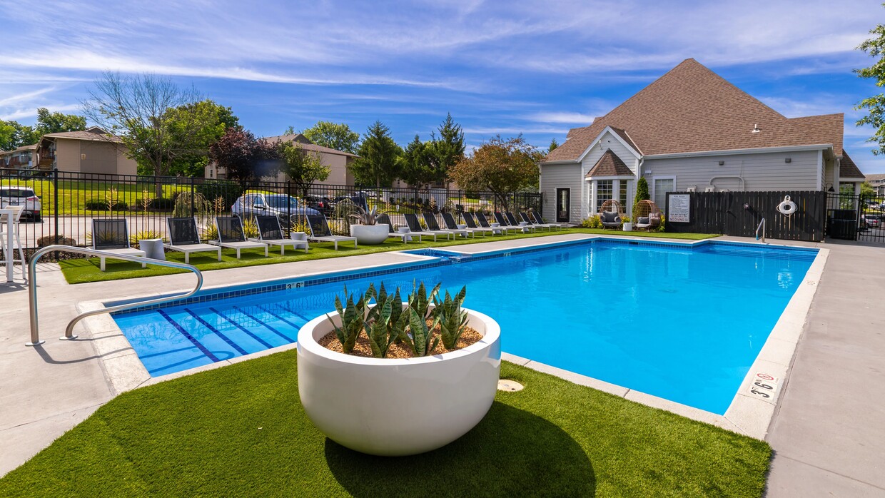 Relájese y descanse en nuestra serena área junto a la piscina, que cuenta con cómodos sillones, exuberante vegetación y un ambiente tranquilo perfecto para darse un refrescante baño o tomar el sol. - Market 1900 Apartment Homes