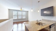 Located at 3245 Glenn McConnell Pkwy in Charleston, SC, this single-floor unit offers a well-designed layout that maximizes every square foot of its compact footprint. The open-concept living and kitchen area is anchored by rich hardwood flooring throughout, creating a warm and cohesive aesthetic. A ceiling fan with overhead lighting keeps the living area comfortable, while a bank of windows fitted with horizontal blinds invites natural light and lends a bright, airy feel to the space.

The kitchen is a standout feature, equipped with a full suite of stainless steel appliances including a refrigerator, electric range, built-in microwave, and dishwasher. Dark espresso cabinetry provides generous storage and contrasts elegantly with the granite countertops. A peninsula with a granite surface and undermount sink serves as both a functional prep area and a casual dining or gathering space, complemented by stylish pendant lighting above.

The bathroom is clean and functional, featuring a full tub-and-shower combination, a dark vanity with granite countertop, and coordinating hardwood-style flooring. A dedicated closet provides practical storage to keep the living spaces uncluttered. The unit's neutral color palette and consistent finishes throughout give it a polished, move-in-ready appeal.