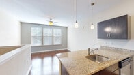 Located at 3245 Glenn McConnell Pkwy in Charleston, SC, this single-floor unit offers a well-designed layout that maximizes every square foot of its compact footprint. The open-concept living and kitchen area is anchored by rich hardwood flooring throughout, creating a warm and cohesive aesthetic. A ceiling fan with overhead lighting keeps the living area comfortable, while a bank of windows fitted with horizontal blinds invites natural light and lends a bright, airy feel to the space.

The kitchen is a standout feature, equipped with a full suite of stainless steel appliances including a refrigerator, electric range, built-in microwave, and dishwasher. Dark espresso cabinetry provides generous storage and contrasts elegantly with the granite countertops. A peninsula with a granite surface and undermount sink serves as both a functional prep area and a casual dining or gathering space, complemented by stylish pendant lighting above.

The bathroom is clean and functional, featuring a full tub-and-shower combination, a dark vanity with granite countertop, and coordinating hardwood-style flooring. A dedicated closet provides practical storage to keep the living spaces uncluttered. The unit's neutral color palette and consistent finishes throughout give it a polished, move-in-ready appeal.