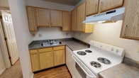 Park Lake is a single-floor unit designed with functionality and comfort in mind. The kitchen is efficiently laid out in an L-shape, featuring warm honey-toned oak cabinetry with ample upper and lower storage, dark laminate countertops, a stainless steel double-basin sink, and a white coil-burner electric range with an overhead ventilation hood. Wood-look flooring runs throughout the kitchen, adding warmth to the space.

The living and dining area is bright and welcoming, with neutral-toned carpet underfoot and a classic chandelier overhead that adds a touch of character. A closet is conveniently accessible from this area, along with direct entry access.

The bedrooms are generously proportioned, each featuring soft carpeting, neutral white walls, and windows fitted with blinds that allow for natural light while maintaining privacy. The rooms offer a clean, open canvas suitable for a variety of furniture arrangements.

The bathroom is straightforward and practical, with a tub and shower combination, a toilet, and wood-look flooring that complements the rest of the unit. The layout is compact yet efficient. Overall, Park Lake offers a clean, well-maintained living environment with a cohesive, no-fuss design throughout.