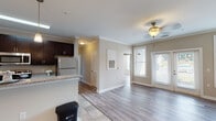 This single-floor residence offers a thoughtfully designed layout with a seamless blend of comfort and modern style. The open-concept living and dining area is anchored by warm hardwood-style flooring, crown molding, and a ceiling fan with light fixture. French doors and multiple windows flood the space with natural light while offering views of the surrounding neighborhood. The kitchen is well-equipped with rich dark cabinetry, granite countertops, stainless steel appliances including a refrigerator, range, and microwave, along with a peninsula with pendant lighting that connects the kitchen to the dining area. The bedrooms are generously sized, each featuring the same hardwood-style flooring, neutral wall tones, and ample natural light from large windows fitted with blinds. The bathrooms are finished with large-format tile flooring, dark vanity cabinetry, granite countertops, and clean white panel doors, providing a polished and cohesive aesthetic. Additional features include a dedicated entry area, interior doors with arched panel detailing, and consistent neutral tones throughout that lend the space a calm, welcoming ambiance. The overall design is practical yet refined, making it a comfortable and move-in-ready living space.
