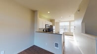 Located at 1869 S River Square in Portland, OR, this apartment spans three floors, offering a well-organized and functional layout throughout. The main living area features warm hardwood flooring that flows seamlessly from the open-concept living space into the kitchen. The kitchen is appointed with white cabinetry, granite countertops, a breakfast bar peninsula, stainless steel appliances including a refrigerator and microwave, and a dishwasher — all framed by windows that invite natural light into the space. A ceiling fan overhead adds comfort to the living area. A half bathroom on one level features a wide vanity with dark countertops, a large mirror, and hardwood flooring. The full bathroom includes a tiled soaking tub and shower combination, white cabinetry, and a dark-topped vanity. The bedroom is carpeted and benefits from a large window with outdoor views of the surrounding neighborhood. A dedicated laundry area houses a full-size washer and dryer with shelving nearby. The lower level includes a private attached garage with an automatic opener, offering generous storage and secure parking. The overall ambiance is clean, neutral, and move-in ready, with consistent finishes throughout each floor.