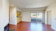 Located on N Sierra Bonita Ave in the vibrant West Hollywood neighborhood of Los Angeles, this 2-bedroom, 2-bathroom residence offers a well-designed single-floor layout with a clean, modern aesthetic throughout. Rich hardwood-style flooring flows consistently across the living spaces, creating warmth and visual continuity.

The open living room serves as the heart of the home, anchored by a classic fireplace and recessed lighting overhead. A kitchen area with light maple cabinetry and dark countertops sits adjacent, providing a functional and stylish workspace. Sliding glass doors open directly onto a private balcony, filling the living area with natural light and offering pleasant outdoor views of the surrounding neighborhood, including mature palm trees.

The primary bedroom is generously proportioned, featuring dual mirrored sliding closets, recessed lighting, and its own sliding door access to the balcony. The second bedroom is bright and clean with hardwood-style flooring and ample wall space. Three closets throughout the unit provide excellent storage capacity.

Both bathrooms are finished with neutral tile work, warm wood vanities, gray countertops, and full soaking tub-shower combinations with handheld fixtures. A central hallway connects all rooms efficiently, completing this well-organized and comfortable Los Angeles residence.