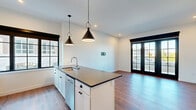 Located at 304 E Jackson Blvd in Elkhart, Indiana, this well-appointed one-bedroom, one-bathroom unit offers a thoughtfully designed open-concept layout that seamlessly connects the kitchen, dining, and living areas. Warm hardwood-style flooring runs throughout the entire space, complementing the clean white walls and bold black accents that define its modern aesthetic.

The kitchen is a standout feature, equipped with stainless steel appliances including a full-size refrigerator, range, and microwave. White shaker-style cabinetry pairs with dark countertops and a subway tile backsplash, while a spacious center island with a built-in sink provides additional prep space and seating potential. Matte black pendant lights add a contemporary finishing touch overhead.

The living area is bright and airy, benefiting from large black-framed windows and French doors that open to an outdoor balcony, flooding the space with natural light and offering views of the surrounding neighborhood. The generously sized bedroom features its own large window with a ceiling fan, multiple closets, and in-unit washer access nearby.

The bathroom is clean and functional, featuring a walk-in shower, white cabinetry, and dark countertop storage. With three closets throughout, storage is plentiful. The unit's modern finishes and open design create a comfortable, stylish living environment.