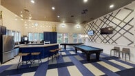 This well-appointed community clubhouse offers a cohesive and sophisticated design anchored by a bold navy-and-cream color palette carried throughout its interconnected spaces. The main game room commands attention with soaring ceilings, a striking blue-and-cream checkered carpet, and an abundance of natural light streaming through large French doors and multi-pane windows that frame views of lush greenery. Two full-size billiards tables and a shuffleboard table make it an ideal gathering spot, while a sleek lounge area features textured navy wall panels, white wainscoting, a wall-mounted flat-screen TV, and plush leather seating. A dedicated cyber café area provides built-in workstations along a navy cabinetry wall adorned with decorative gold plate art, complemented by orb pendant lighting and a high-top table for collaborative work. Adjacent to this is a Starbucks coffee station set within navy cabinetry beneath a bank of windows, offering a bright and inviting refreshment nook. A social seating area with high-top tables flanks dramatic navy textured accent walls framed by white columns. Throughout, dark ceilings contrast elegantly with warm lighting fixtures, including geometric chandeliers and sculptural pendants, creating an upscale, welcoming ambiance.