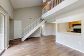 Located at 333 Lake in the Woods Drive in Melbourne, FL, this two-bedroom, three-bathroom two-story home offers a well-designed layout spread across two floors. The main level is anchored by a dramatic, open-concept living area with soaring vaulted ceilings, wood-look flooring, and a ceiling fan overhead. A white-railed staircase leads to the upper loft level, adding architectural interest and a sense of openness to the space. The kitchen features warm honey-toned cabinetry, black appliances including a range and refrigerator, and a pass-through window that connects it to the living and dining areas — ideal for an open, communicative flow. The dining and kitchen areas are thoughtfully integrated on the main level alongside the living room. Both bedrooms are carpeted and include ceiling fans, with the generously sized primary bedroom offering natural light through dual windows. Multiple closets, including a walk-in with built-in wire shelving, provide ample storage throughout. The three bathrooms feature wood-toned cabinetry and wood-look flooring. Two balconies extend the living space outdoors, while a dedicated utility room adds everyday practicality. The upper loft provides flexible additional space ideal for a home office or sitting area.