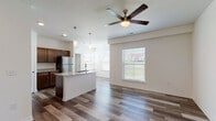 Located on Evergreen Street in Gardner, Kansas, this single-floor residence offers a thoughtfully designed layout with modern finishes and a bright, welcoming atmosphere. The open-concept living and kitchen area serves as the heart of the home, featuring rich hardwood-style flooring, neutral walls, and generous natural light streaming through multiple windows with blinds. A ceiling fan anchors the living space, enhancing both comfort and airflow.

The kitchen is a standout, equipped with a central island featuring a granite countertop and integrated sink, complemented by dark wood cabinetry, stainless steel appliances — including a refrigerator, range, and microwave — and matching granite countertops throughout. Pendant lighting above the island adds a refined touch.

The bedrooms offer a comfortable retreat, with plush carpeting, ceiling fans, and ample closet space, including walk-in options. One bedroom features hardwood-style flooring and multiple closet doors for generous storage.

The bathroom is finished with a dual-sink vanity topped with white countertops, dark wood cabinetry, a large mirror, and hardwood-style flooring, offering both style and functionality. Overall, the space combines practical design with contemporary finishes for a cohesive and inviting living environment.