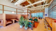 Located at 1525 N American St in Philadelphia, PA, this distinctive single-floor space offers a generous, open layout that masterfully combines Japanese-inspired design with contemporary industrial elements. Soaring exposed ceilings reveal structural beams, ductwork, and track lighting, adding an airy, loft-like character throughout.

The living area is a standout, anchored by a dramatic floor-to-ceiling glass block wall that bathes the room in diffused natural light. Warm terracotta tile flooring runs throughout, complementing the rich wood-toned paneling and booth-style seating areas that evoke a refined, intimate atmosphere. Teal upholstered lounge chairs and sofas are arranged thoughtfully around low coffee tables, while lush potted plants add organic warmth to the space.

Sliding wood-panel partitions provide flexible room division, allowing the open layout to be reconfigured as needed. A media area features a large flat-screen television and additional seating, framed by the striking glass block wall.

The kitchen is equally impressive, featuring warm natural wood cabinetry, white stone countertops, and a deep green ceramic tile backsplash. A large central island with an integrated cooktop and a stainless steel range hood serves as the kitchen's focal point, while open shelving displays curated ceramics and greenery, reinforcing the space's artful, welcoming aesthetic.