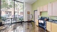 This 550 square foot studio apartment in Chicago offers a contemporary living experience in a compact space. The unit is thoughtfully designed with an open floor plan that maximizes functionality. The kitchen area is equipped with modern appliances, including a full-sized refrigerator and stove, complemented by light wood cabinetry and a green accent wall that adds a pop of color.

The living space is versatile, with ample room for both sleeping and lounging areas. Large windows flood the room with natural light and offer views of the urban streetscape, creating an airy atmosphere. The polished concrete floors throughout add an industrial chic touch while being easy to maintain.

The bathroom is surprisingly spacious for a studio, featuring a full-sized bathtub with shower, a vanity with storage, and modern fixtures. The bedroom area, while not separated, can be easily defined with furniture placement and includes space for a dresser and full-length mirror.

Throughout the apartment, recessed lighting and a dropped ceiling contribute to the modern aesthetic. The unit also includes practical amenities such as in-unit laundry facilities. With its efficient layout and contemporary design, this studio apartment is ideal for urban professionals or students seeking a stylish living space in the heart of Chicago.