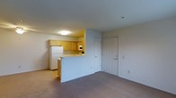 Located at 1602 A Ashby Square Dr, this single-floor unit offers a practical and well-organized layout designed for comfortable everyday living. The open-concept design connects the living area to the kitchen via a pass-through counter, creating a sense of openness and ease of movement throughout the space. The living area features wall-to-wall carpeting in a neutral tone, contributing to a warm and inviting atmosphere. The kitchen is equipped with light wood cabinetry that extends to the upper walls, providing ample storage space. A white refrigerator, built-in microwave, and additional appliances are neatly integrated into the kitchen layout. The pass-through counter serves both as a functional workspace and an informal dining or serving surface. The unit's interior is finished with clean white walls and flush-mount ceiling lighting, keeping the space bright and clean. A paneled entry door with decorative molding adds a classic touch to the overall aesthetic. The straightforward, efficient floor plan makes excellent use of the available space, ensuring that each area serves a clear purpose while maintaining an open and uncluttered feel throughout.