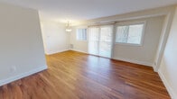 This single-floor, three-bedroom, one-bathroom unit offers an efficient and well-organized layout across a modest footprint. Warm hardwood flooring runs consistently throughout the space, lending a cohesive and polished look to each room.

The combined living and dining area serves as the heart of the unit, featuring a pendant light fixture and large sliding glass doors flanked by windows that invite abundant natural light and provide outdoor views. This open area connects naturally to the kitchen, which has been updated with white shaker-style cabinetry, light quartz countertops, a subway tile backsplash, and a full suite of stainless steel appliances including a refrigerator, range, dishwasher, and built-in microwave.

The three bedrooms are modestly sized, with the primary bedroom offering slightly more space. Each bedroom continues the hardwood flooring theme and includes closet storage, with at least one featuring a dedicated walk-in closet with full-length hanging rods and shelving.

The bathroom is clean and contemporary, equipped with a pedestal sink, a framed mirror, and a frosted glass sliding shower enclosure. The overall ambiance of the unit is bright, neutral, and move-in ready.