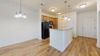 Located at 11505 Masterton Rd in Charlotte, NC, this well-appointed 2-bedroom, 2-bathroom residence offers a thoughtfully designed single-level layout. The open living room features rich hardwood-style flooring, crown molding, a ceiling fan, and a glass door that floods the space with natural light and provides access to an outdoor balcony. The kitchen is equipped with warm wood cabinetry, granite-style countertops, a breakfast bar island with pendant lighting, a tile backsplash, and black appliances including a refrigerator, range, and microwave. Both bedrooms are carpeted, bright, and well-sized, each featuring ceiling fans and large windows with views of the surrounding neighborhood. The primary bedroom includes a walk-in closet with built-in wire shelving. The bathroom features a granite-top vanity with warm wood cabinetry, hardwood-style flooring, and a combination tub and glass-enclosed shower. A dedicated laundry area accommodates a full-size washer and dryer with overhead shelving for added storage. Throughout the residence, neutral tones, clean finishes, and consistent design elements create a cohesive and comfortable living environment.