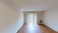 This single-floor residential unit offers a practical and comfortable layout across several well-defined living spaces. The living room serves as the heart of the home, featuring warm hardwood flooring that extends throughout the main living areas and a large sliding glass door dressed with vertical blinds, allowing generous natural light to fill the space. A wall-mounted heating unit sits conveniently nearby, and a closet with louvered doors adds built-in storage adjacent to the entryway.

The galley-style kitchen is efficiently designed with honey-toned wood cabinetry, dark granite-look countertops, a stainless steel sink, and a full-size black refrigerator. A doorway from the kitchen connects to the surrounding areas, maintaining a functional flow throughout the unit.

Two bedrooms feature plush neutral carpeting and vertical-blind-covered windows that bring in natural light while offering privacy. The rooms provide a calm, understated atmosphere with clean beige walls and simple, classic finishes.

The bathroom is well-appointed with tile flooring, a wood-vanity with an integrated sink, a large mirror with overhead lighting, and a shower-tub combination. Overall, this unit presents a clean, move-in-ready space with consistent finishes and a straightforward, livable design.