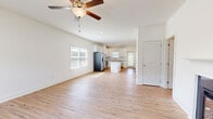 This single-story home offers a thoughtfully designed layout across a comfortable footprint, with light hardwood flooring flowing consistently throughout every room. The open-concept living area serves as the heart of the home, featuring a ceiling fan, a fireplace, and windows that invite natural light. This space connects seamlessly to the kitchen, which is outfitted with white shaker cabinetry, granite countertops, a subway tile backsplash, stainless steel appliances including a refrigerator and dishwasher, and a central island providing additional workspace and storage.

The generously sized primary bedroom includes a walk-in closet with wire shelving and an en-suite bathroom featuring granite-topped vanity cabinetry. The additional bedrooms each include double-door closets and share access to a second full bathroom. A dedicated laundry room houses a full-size washer and dryer with overhead shelving for added storage convenience.

The attached two-car garage features a concrete floor, an automatic opener, and a paneled door with windowed sections. Throughout the home, clean white walls, recessed lighting, and uniform flooring create a bright, cohesive aesthetic.