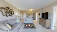 Located at 600 Valley Rd in Warrington, PA, this single-floor residence offers a well-designed layout that balances comfort and functionality. The living area serves as the heart of the home, featuring plush wall-to-wall carpeting that adds warmth underfoot and a neutral color palette throughout that creates a bright, airy atmosphere. The space is thoughtfully arranged with ample room for seating and entertaining, highlighted by a pair of coordinating gray sofas accented with colorful throw pillows and centered around a rustic wood coffee table. A media console with a flat-screen television anchors one side of the room, while decorative open shelving and wall-mounted accents add character and depth to the walls. Track lighting overhead provides adjustable illumination, complementing the room's overall brightness. A pass-through opening connects the living area to the kitchen beyond, enhancing the open flow of the floor plan. Doorways lead to additional areas of the home, suggesting a practical and connected layout. The overall ambiance is welcoming and move-in ready, making this Warrington property a comfortable and stylish place to call home.