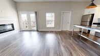 This contemporary apartment offers a blend of comfort and functionality. The living area boasts wood-look flooring and a sleek electric fireplace, creating a warm and inviting atmosphere. The kitchen is a highlight, featuring stainless steel appliances, white cabinetry, and a subway tile backsplash, perfect for culinary enthusiasts. The bedroom is generously sized with plush carpeting and a large window for natural light. A standout feature is the walk-in closet with ample wire shelving, providing excellent storage solutions. The bathroom is modern with a vanity offering plenty of counter space and a shower/tub combination. The unit also includes an in-unit laundry area with a washer and dryer, adding convenience to daily life. Throughout the apartment, neutral tones dominate, allowing for personalization. The ceiling fans and window treatments contribute to the overall comfort and privacy of this well-designed living space.