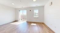Located at 200 N Main St in Evansville, Indiana, this efficiently designed single-floor unit offers a well-appointed layout that maximizes every square foot. The open-concept kitchen and living area serves as the heart of the space, featuring warm hardwood-style flooring throughout, crisp white walls, and recessed lighting. The kitchen is outfitted with white shaker-style cabinetry extending to the ceiling, granite countertops, a subway tile backsplash, and a full suite of stainless steel appliances including a refrigerator, electric range, over-the-range microwave, and a sink with modern fixtures. The living area is bright and airy, benefiting from natural light streaming through multiple windows and sliding glass doors that open to a private balcony with outdoor views. The bathroom continues the clean aesthetic with white cabinetry, granite countertops, a well-lit vanity mirror, and a glass-enclosed shower. A dedicated laundry area with a louvered-door closet adds everyday convenience. Additional storage is provided by a walk-in closet with wire shelving. The unit's consistent use of light tones, quality finishes, and natural light creates a modern, functional living environment.
