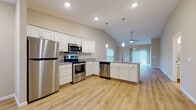Located at 9422 Darrow Rd in Twinsburg, Ohio, this single-floor home showcases a thoughtfully designed open-concept layout with a clean, modern aesthetic. The kitchen is a standout feature, outfitted with white shaker-style cabinetry, granite-look countertops, a full suite of stainless steel appliances including a refrigerator, range, microwave, and dishwasher, and a peninsula that flows seamlessly into the living and dining areas. Vaulted ceilings with ceiling fans amplify the sense of openness, while natural light filters in through multiple windows dressed with blinds. Light-toned hardwood-style flooring runs throughout the main living areas, adding warmth and continuity. The living space extends toward a glass door that invites additional natural light. Bedrooms are carpeted for comfort, with one featuring a spacious walk-in closet equipped with a full shelving and hanging system. The bathrooms are finished with white vanities, granite-look countertops, and light hardwood-style flooring — one includes a walk-in shower, and another offers a shower-tub combo. A mudroom-style entry area with closet storage and a windowed exterior door provides a practical and welcoming point of entry.