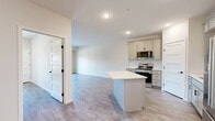 Located at 7545 Sunwood Dr NW in Ramsey, MN, this 2-bedroom, 1-bathroom unit offers a thoughtfully designed single-floor layout with modern finishes throughout. Luxury vinyl plank flooring flows consistently through every room, providing both durability and a clean, contemporary aesthetic.

The open kitchen is a standout feature, equipped with gray shaker-style cabinetry, stainless steel appliances including a French door refrigerator, electric range, microwave, and dishwasher, a white quartz countertop, subway tile backsplash, and a central island ideal for meal prep or casual dining. Recessed lighting illuminates the space effectively.

The adjoining living room is bright and open, featuring a sliding glass door that leads to a private balcony with outdoor views, allowing natural light to fill the space. The primary bedroom is generously sized with a ceiling fan, a large window, and access to a closet. The second bedroom also features a window with exterior views, a closet, and panel-style doors.

The full bathroom is well-appointed with gray vanity cabinetry, white quartz countertops, a framed mirror, lighted vanity fixture, and a shower-tub combo. Two closets provide additional storage throughout the unit. Neutral warm-toned walls and clean white trim complete the polished, move-in-ready interior.