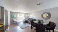 This single-floor residence presents a thoughtfully designed layout that balances open communal spaces with comfortable private retreats. The living and dining area forms the heart of the home, featuring wood-look flooring, a textured ceiling, and neutral gray walls that provide a versatile backdrop. A sliding glass door floods the living space with natural light and provides access to an outdoor balcony area. The dining space accommodates a glass-top table, while the living area offers ample room for generous seating arrangements.

The kitchen is equipped with white cabinetry, dark granite-style countertops, black appliances including a refrigerator, electric range, and dishwasher, and a recessed ceiling fixture that adds warmth. A convenient breakfast bar connects the kitchen to the main living area.

Two bedrooms feature plush carpeting, gray walls, and textured ceilings. The primary bedroom includes a mirrored sliding-door closet, while the secondary bedroom also offers dedicated closet storage. Both rooms are well-proportioned and receive natural light.

Two bathrooms serve the residence—one featuring a walk-in shower and the other a full tub-shower combination—each with wood-look flooring and clean white fixtures.