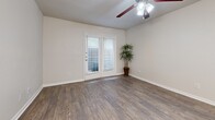 Located at 7414 E Grand Ave in Dallas, TX, this one-bedroom, one-bathroom unit offers an efficient and well-designed single-floor layout. The open-concept living, dining, and kitchen area serves as the heart of the home, featuring rich wood-look hardwood flooring, neutral toned walls, and a ceiling fan with integrated lighting. French doors flood the space with natural light and open directly onto a private patio, extending the living area outdoors. The kitchen is a standout feature, showcasing gray-toned cabinetry, granite-style countertops, a peninsula island with a built-in sink and pendant lighting, stainless steel appliances including a gas range, microwave, and refrigerator, and a classic subway tile backsplash. A chandelier adds an elegant touch to the adjoining dining area. The bedroom is a comfortable retreat with plush carpeting, a natural light-filled window, and access to three closets offering generous storage throughout the unit. The bathroom is finished with a dark wood vanity, granite countertop, and a tub-shower combination. A dedicated laundry area and a hallway complete this thoughtfully arranged home.