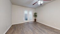 Located at 7414 E Grand Ave in Dallas, TX, this one-bedroom, one-bathroom unit offers an efficient and well-designed single-floor layout. The open-concept living, dining, and kitchen area serves as the heart of the home, featuring rich wood-look hardwood flooring, neutral toned walls, and a ceiling fan with integrated lighting. French doors flood the space with natural light and open directly onto a private patio, extending the living area outdoors. The kitchen is a standout feature, showcasing gray-toned cabinetry, granite-style countertops, a peninsula island with a built-in sink and pendant lighting, stainless steel appliances including a gas range, microwave, and refrigerator, and a classic subway tile backsplash. A chandelier adds an elegant touch to the adjoining dining area. The bedroom is a comfortable retreat with plush carpeting, a natural light-filled window, and access to three closets offering generous storage throughout the unit. The bathroom is finished with a dark wood vanity, granite countertop, and a tub-shower combination. A dedicated laundry area and a hallway complete this thoughtfully arranged home.