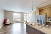 This thoughtfully designed 2-bedroom, 3-bathroom residence offers a functional and modern single-floor layout. The entrance flows into an open-concept living and kitchen area bathed in natural light from expansive windows fitted with horizontal blinds, framing urban skyline views. The living room features light hardwood-style flooring, neutral tones, and track lighting, creating a bright and versatile space. The kitchen is a standout feature, equipped with stainless steel appliances including a refrigerator, microwave, and range, complemented by warm wood cabinetry, quartz countertops, an undermount sink, and a peninsula with pendant lighting — ideal for both cooking and casual dining. The primary bedroom offers plush carpeting, a ceiling fan, and a window with outdoor views, along with double closets for ample storage. The second bedroom also features carpet flooring and its own closet access. Three bathrooms serve the residence, including a clean, all-white tiled bathroom with a tub and built-in shelving. A notable highlight is the private outdoor deck, outfitted with wood decking and sleek metal railings, overlooking a waterway and bridge — providing a striking urban backdrop for outdoor relaxation.