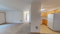 Located at 3051 Gehlar Rd NW in Salem, Oregon, this single-floor unit offers a practical and straightforward layout designed for comfortable everyday living. The kitchen is well-equipped with warm honey-toned wood cabinetry extending to the ceiling for generous storage, light countertops, and white appliances including an electric range, built-in microwave, and a full-sized refrigerator. Tile flooring in the kitchen provides durability and ease of maintenance.

The living area transitions to plush wall-to-wall carpeting, creating a warm, comfortable atmosphere. A structural column defines the boundary between the kitchen and living space, adding architectural character while maintaining an open feel. Natural light filters in through windows fitted with blinds, with views of the surrounding greenery.

The bedrooms are carpeted and well-lit, each featuring windows that frame outdoor views of landscaped surroundings. The primary bedroom benefits from multiple windows and a ceiling fan with integrated lighting, enhancing airflow and brightness. The bathroom includes tile flooring, a wooden vanity with a light countertop, and accessibility grab bars near the shower area. The overall design is clean and neutral, offering a move-in ready environment throughout.