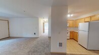 Located at 3051 Gehlar Rd NW in Salem, Oregon, this single-floor unit offers a practical and straightforward layout designed for comfortable everyday living. The kitchen is well-equipped with warm honey-toned wood cabinetry extending to the ceiling for generous storage, light countertops, and white appliances including an electric range, built-in microwave, and a full-sized refrigerator. Tile flooring in the kitchen provides durability and ease of maintenance.

The living area transitions to plush wall-to-wall carpeting, creating a warm, comfortable atmosphere. A structural column defines the boundary between the kitchen and living space, adding architectural character while maintaining an open feel. Natural light filters in through windows fitted with blinds, with views of the surrounding greenery.

The bedrooms are carpeted and well-lit, each featuring windows that frame outdoor views of landscaped surroundings. The primary bedroom benefits from multiple windows and a ceiling fan with integrated lighting, enhancing airflow and brightness. The bathroom includes tile flooring, a wooden vanity with a light countertop, and accessibility grab bars near the shower area. The overall design is clean and neutral, offering a move-in ready environment throughout.
