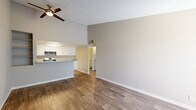 This single-floor unit offers a cohesive, neutral design highlighted by warm wood-style flooring that runs consistently throughout the space. The open layout connects the living area to the kitchen, which features white cabinetry, granite-look countertops, a double-basin sink, a gas range, dishwasher, and a refrigerator — providing ample functionality and storage. A peninsula counter separates the kitchen from the living space, enhancing the open feel.

The living area benefits from a ceiling fan, built-in wall shelving, and a sliding glass door dressed with vertical blinds that invites natural light and provides access to an outdoor area. A secondary room — also with a sliding glass door — offers the same brightness and outdoor connectivity, making it versatile as a bedroom or additional living space.

The bedroom features wood-style flooring, neutral walls, and a six-panel door, maintaining the clean aesthetic found throughout the unit. The bathroom is appointed with a granite-top vanity, a tub/shower combination with a curved curtain rod, and coordinating wood-style flooring. Textured ceilings appear in several rooms, adding subtle architectural character to the overall space.