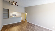 This single-floor unit offers a cohesive, neutral design highlighted by warm wood-style flooring that runs consistently throughout the space. The open layout connects the living area to the kitchen, which features white cabinetry, granite-look countertops, a double-basin sink, a gas range, dishwasher, and a refrigerator — providing ample functionality and storage. A peninsula counter separates the kitchen from the living space, enhancing the open feel.

The living area benefits from a ceiling fan, built-in wall shelving, and a sliding glass door dressed with vertical blinds that invites natural light and provides access to an outdoor area. A secondary room — also with a sliding glass door — offers the same brightness and outdoor connectivity, making it versatile as a bedroom or additional living space.

The bedroom features wood-style flooring, neutral walls, and a six-panel door, maintaining the clean aesthetic found throughout the unit. The bathroom is appointed with a granite-top vanity, a tub/shower combination with a curved curtain rod, and coordinating wood-style flooring. Textured ceilings appear in several rooms, adding subtle architectural character to the overall space.