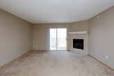 This single-floor unit offers a practical and comfortable layout designed for everyday living. The open living area is a standout feature, highlighted by a tile-surround fireplace and a sliding glass door that leads to a private balcony, filling the carpeted space with natural light. A ceiling fan adds to the room's comfort. Adjacent to the living area, the galley-style kitchen is efficiently designed with warm honey-toned wood cabinetry, dark speckled countertops, and wood-look flooring. It is fully equipped with a full-size refrigerator, electric range, built-in microwave, dishwasher, and a double-basin sink, providing ample functionality. The bedrooms are carpeted and finished with neutral tones, offering a quiet and restful atmosphere. One bedroom benefits from a window with an outdoor view, while the other connects conveniently to the kitchen area. The full bathroom features earthy stone-look tile flooring and a white soaking tub-shower combination. A spacious walk-in closet with built-in shelving and multiple hanging rods provides excellent storage capacity. Throughout the unit, consistent warm-toned trim and neutral wall colors create a cohesive and inviting ambiance.