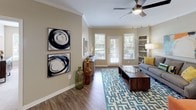 This thoughtfully designed two-bedroom, two-bathroom residence provides a comfortable and functional single-floor layout. The living room serves as the heart of the home, featuring wood-style flooring, crown molding, a ceiling fan, built-in shelving, and large windows with outdoor views that fill the space with natural light. A dedicated dining area adjoins the living space, highlighted by a pendant light fixture and wood-style flooring that carries throughout the common areas.

The kitchen is well-appointed with stainless steel appliances including a range, microwave, and refrigerator, complemented by warm wood cabinetry, granite-style countertops, a breakfast bar, and a walk-in pantry for added storage.

The primary bedroom offers plush carpeting, a ceiling fan, a built-in desk with overhead cabinetry, and open shelving. Its en-suite bathroom includes a walk-in shower with decorative tile accents, a vanity with granite-style countertops, and wood-style flooring. The second bedroom is spacious with carpet, a large window overlooking greenery, and access to a full bathroom featuring a soaking tub and shower combination with decorative tile detailing. Throughout the residence, neutral tones and crown molding create a cohesive and inviting ambiance.