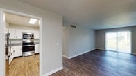 This well-appointed single-floor residence offers a thoughtfully designed layout with modern finishes throughout. The kitchen serves as a standout feature, showcasing crisp white shaker-style cabinetry with matte black hardware, granite countertops, and a full suite of stainless steel appliances including a range with overhead microwave, dishwasher, and refrigerator. A skylight overhead fills the kitchen with natural light, while wood-look flooring adds warmth and continuity. The open living area flows directly from the kitchen, featuring the same durable wood-look flooring and neutral gray walls that create a clean, versatile backdrop. Generous wall space and multiple outlets make the living area highly functional and easy to furnish. The bedrooms are finished with soft carpeting and neutral tones, offering a comfortable and quiet retreat. Windows allow natural light to filter in, enhancing the welcoming ambiance. The bathroom is finished with large-format white subway tile surrounding a full soaking tub and shower combo, complemented by matte black fixtures that provide a sleek, contemporary contrast. Throughout the space, consistent use of neutral tones, modern hardware, and quality finishes create a cohesive and move-in-ready environment.