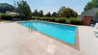 Located at Westgate, this single-floor property offers a well-appointed layout designed for comfortable living and leisure. The standout feature of this space is its expansive outdoor swimming pool, showcasing crystal-clear blue water set within a generously sized concrete surround. The pool is equipped with stainless steel entry rails for easy access and is flanked by a row of lounge chairs, ideal for relaxing under open skies. Lush ornamental grasses and mature trees frame the perimeter of the pool area, providing both natural privacy and a serene, park-like ambiance. The verdant landscaping creates a striking visual backdrop, blending the built environment seamlessly with nature. The outdoor area benefits from abundant natural light, making it an inviting retreat during sunny days. The combination of thoughtful landscaping, generous deck space, and the large pool contributes to a resort-like atmosphere. Overall, the Westgate property delivers a cohesive and well-maintained environment that balances indoor convenience with exceptional outdoor amenities.