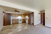 This single-floor, 2-bedroom, 1-bathroom unit offers a practical and comfortable layout designed for everyday living. The open-concept kitchen and living area form the heart of the home, with the kitchen featuring warm oak-toned wood cabinetry, ample upper and lower storage, a tile-patterned floor, and white appliances including a range, dishwasher, and refrigerator. A ceiling fan overhead keeps the space comfortable, and a convenient closet is located just off the kitchen area. The living room flows naturally from the kitchen, finished with neutral carpeting and baseboard heating.

The two bedrooms are carpeted and bright, each equipped with baseboard heating. The primary bedroom is generously sized, featuring large windows that bring in natural light and offer views of mature trees and greenery outside. The second bedroom includes a sliding closet with wood-trimmed doors. Both rooms are connected via hallways that provide a logical, easy-to-navigate floor plan.

The bathroom is well-appointed with a tub-shower combo, a vanity with storage, a large mirror, and tile flooring. Additional storage is provided by hallway closets. Throughout the unit, dark wood trim accents the doors and windows, lending a cohesive, classic character to the overall design.