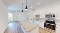 This thoughtfully designed 2-bedroom, 2-bathroom residence in Austin, TX offers a clean, modern aesthetic with consistent finishes throughout. The open-concept kitchen serves as the heart of the home, showcasing crisp white shaker cabinetry extending to the ceiling, a subway tile backsplash, sleek quartz countertops, and a full suite of stainless steel appliances including a refrigerator, range, microwave, and dishwasher. A large central island with pendant lighting provides additional prep space and casual seating, flowing naturally into the living area, which features a ceiling fan and recessed lighting. Light wood-style luxury vinyl plank flooring runs throughout the entire residence, creating a warm, cohesive look. Each bedroom is bright and airy, benefiting from natural light through blinds-equipped windows and ceiling fans for comfort. The primary bedroom offers a generous footprint with dedicated closet space. Both bathrooms maintain a consistent design language, featuring white cabinetry, quartz counters, tub-shower combinations with brushed nickel fixtures, and white tile surrounds. Three closets provide ample storage throughout. The overall ambiance is fresh, bright, and move-in ready, reflecting a contemporary style well-suited for Austin living.
