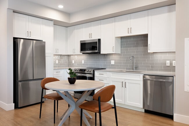 Finish Package I Kitchen with white cabinetry, grey tile backsplash, grey quartz countertops, stainless steel appliances, and hard surface flooring (Representative photo) - Avalon Tech Ridge