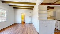 Located in Studio City, this 1-bedroom, 1-bathroom residence showcases a distinctive mid-century architectural character highlighted by prominent exposed wood beams spanning the white-paneled ceilings throughout. Rich hardwood flooring flows consistently across all rooms, lending warmth and cohesion to the entire space.

The open living room is bright and airy, benefiting from large windows that frame views of the surrounding hillside landscape and allow abundant natural light to fill the room. A wall-mounted A/C unit provides climate control. The living area connects seamlessly to the kitchen, which features white cabinetry with ample storage, a double-basin sink, light stone-toned countertops, and a gas range — all accented by the signature beamed ceiling overhead.

The bedroom offers a comfortable footprint with a sliding-door closet, continued hardwood flooring, and exposed beams, creating a consistent and cozy aesthetic. A ceiling fan in the adjoining area enhances ventilation and comfort.

The bathroom is cleanly appointed with tile surround walls in soft cream tones, a combination tub and shower with a handheld showerhead, a pedestal-style vanity, and a rectangular mirror. A hallway connects the principal rooms, completing the efficient and well-organized single-floor layout.