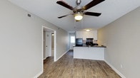 This single-floor 2-bedroom, 1-bathroom home offers a practical and comfortable layout designed for easy everyday living. The open-concept main living area flows directly into the kitchen, creating a connected and functional space ideal for both relaxing and entertaining. Wood-look plank flooring runs throughout, adding warmth and a cohesive feel to the interior. A ceiling fan with integrated lighting anchors the living area, providing both comfort and illumination.

The kitchen features white cabinetry, dark countertops, and black appliances, including a refrigerator and range. A peninsula-style breakfast bar separates the kitchen from the living space while maintaining the open feel. A window above the sink allows natural light to filter into the kitchen area. The textured ceiling and neutral grey-toned walls provide a clean, understated backdrop throughout the home.

A hallway leads to the two bedrooms and the shared bathroom, offering a clear separation between the living and sleeping areas. The bedrooms benefit from the same consistent flooring and neutral color palette found throughout the home. Overall, the space presents a tidy, move-in-ready environment with a straightforward and efficient floor plan well-suited for a variety of occupants.