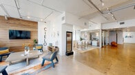Located at 915 West Grape Street in San Diego's vibrant Little Italy district, Cielo offers a thoughtfully designed amenity floor that blends industrial aesthetics with contemporary elegance. The single-floor space spans a generous footprint, encompassing a welcoming lobby, a state-of-the-art fitness center, and open communal areas.

The lobby and lounge area immediately establish a refined tone, featuring polished concrete floors, exposed ductwork, and soaring ceilings fitted with track lighting. A warm wood accent wall bearing the "Cielo" branding anchors one end of the lounge, which is furnished with modern seating, a sleek credenza, and a freestanding water feature. Glass-walled rooms provide visual transparency throughout, while large street-facing windows flood the space with natural light and views of the surrounding neighborhood.

The fitness center is extensively equipped, offering treadmills, free weights, cable machines, TRX suspension trainers, and mirrored walls — all set on durable hardwood flooring. A dedicated bathroom serves the floor.

Throughout the common areas, curated sculptural art pieces and framed works add a gallery-like quality to the circulation spaces. Package lockers and resident mailboxes are thoughtfully integrated into the layout. The overall ambiance is clean, modern, and sophisticated, reflecting a commitment to both function and design.